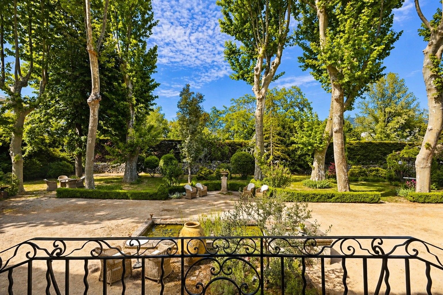 A garden with trees, a pond, and outdoor seating.