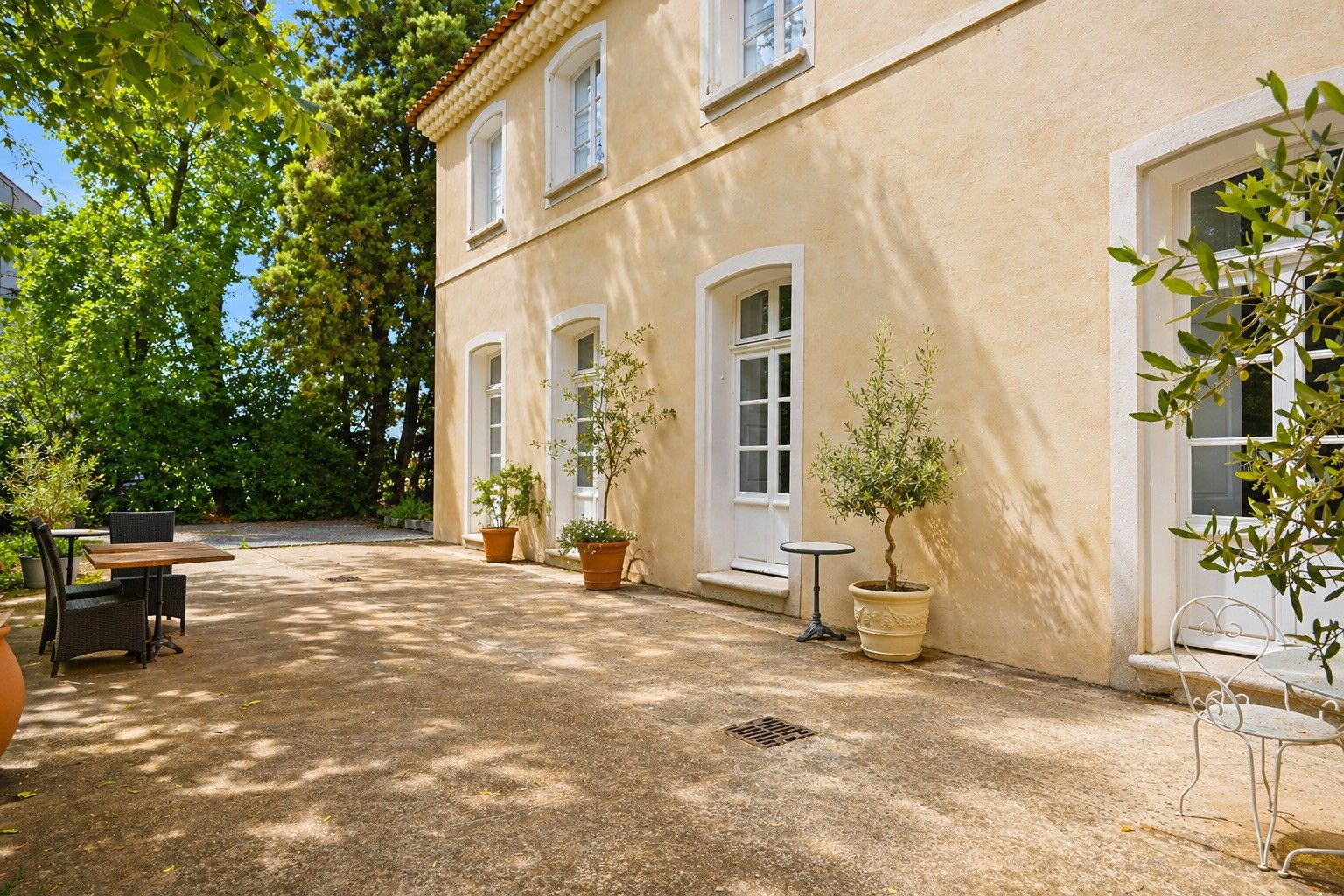 Ein Gebäude mit Innenhof, Außenbestuhlung und Blumentöpfen.