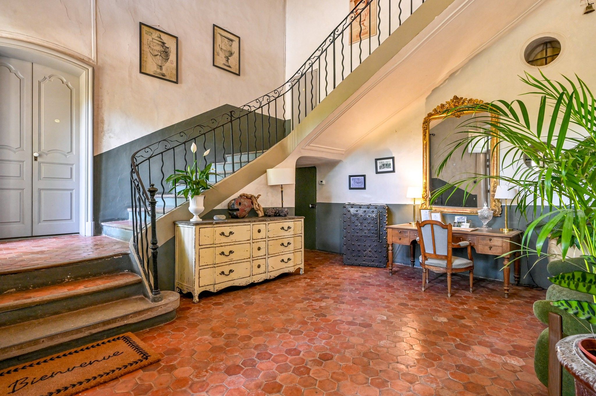 Ein geräumiges Foyer mit Treppe, einem Holzschrank, einem Sessel und einem großen Spiegel.