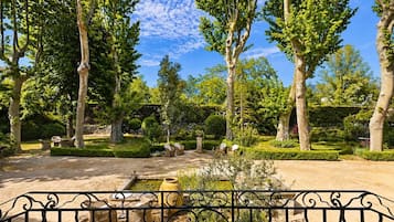 Ein Garten mit Bäumen, einem Teich und Sitzgelegenheiten im Freien.