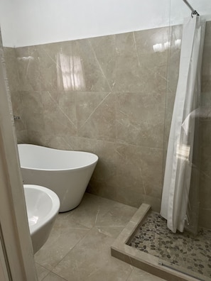 Un baño con una bañera independiente, cabina de ducha y suelo de baldosas.