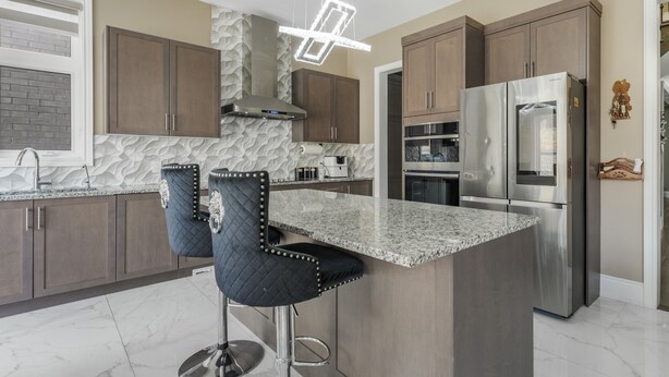 A modern kitchen with granite countertops, stainless steel appliances, and dark wooden cabinets.