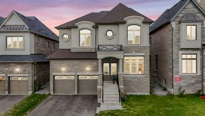 A two-story house with a stone facade, a front entrance with a door, and two garage doors.