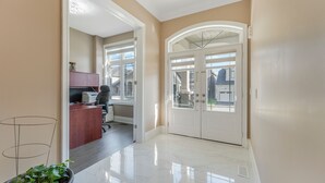 A hallway with a desk, office chair, and a potted plant.