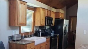 A kitchen with wooden cabinets, a microwave, a refrigerator, and a toaster.