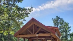 A small cabin with a porch, surrounded by trees.