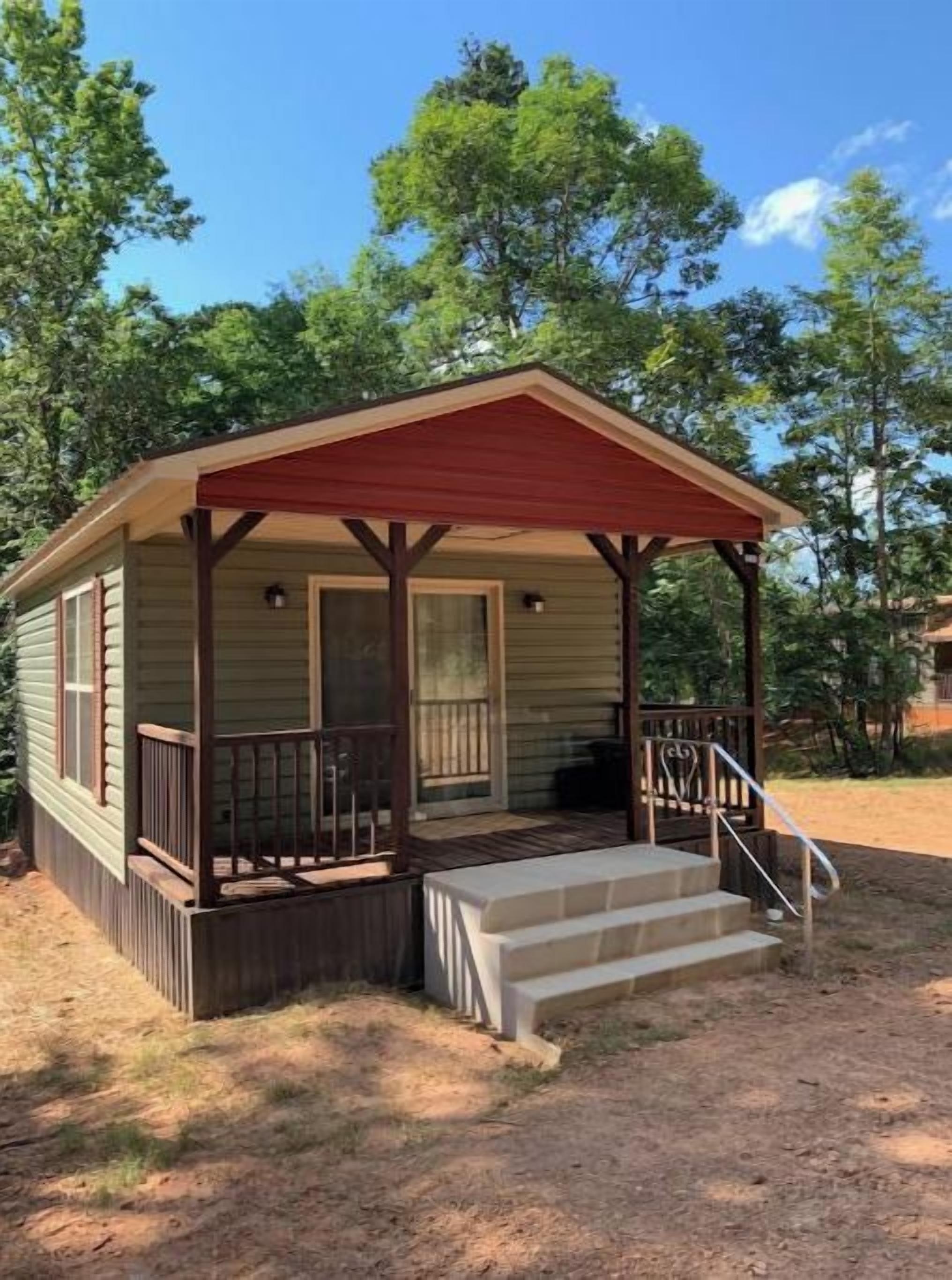 A small, single-story cabin with a porch and steps leading to the entrance.