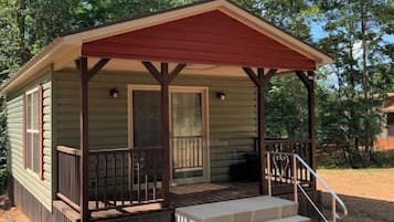 A small, single-story cabin with a porch and steps leading to the entrance.