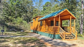 A wooden cabin with a porch and a covered deck, surrounded by trees. - Barnwell Mountain Cabins #6 (Gilmer)