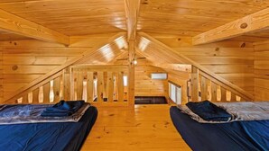 Una cabaña con dos camas, paredes de madera y techo inclinado.