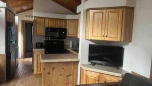 A compact kitchen with wooden cabinets, a microwave, and a built-in TV. - Barnwell Mountain Cabins #8 (Gilmer)