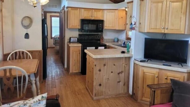 A compact kitchen with wooden cabinets, a microwave, and a stove. - Barnwell Mountain Cabins #8 (Gilmer)