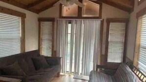 A room with a wooden ceiling, a ceiling fan, a couch, a window with blinds, and a door with a curtain. - Barnwell Mountain Cabins #8 (Gilmer)