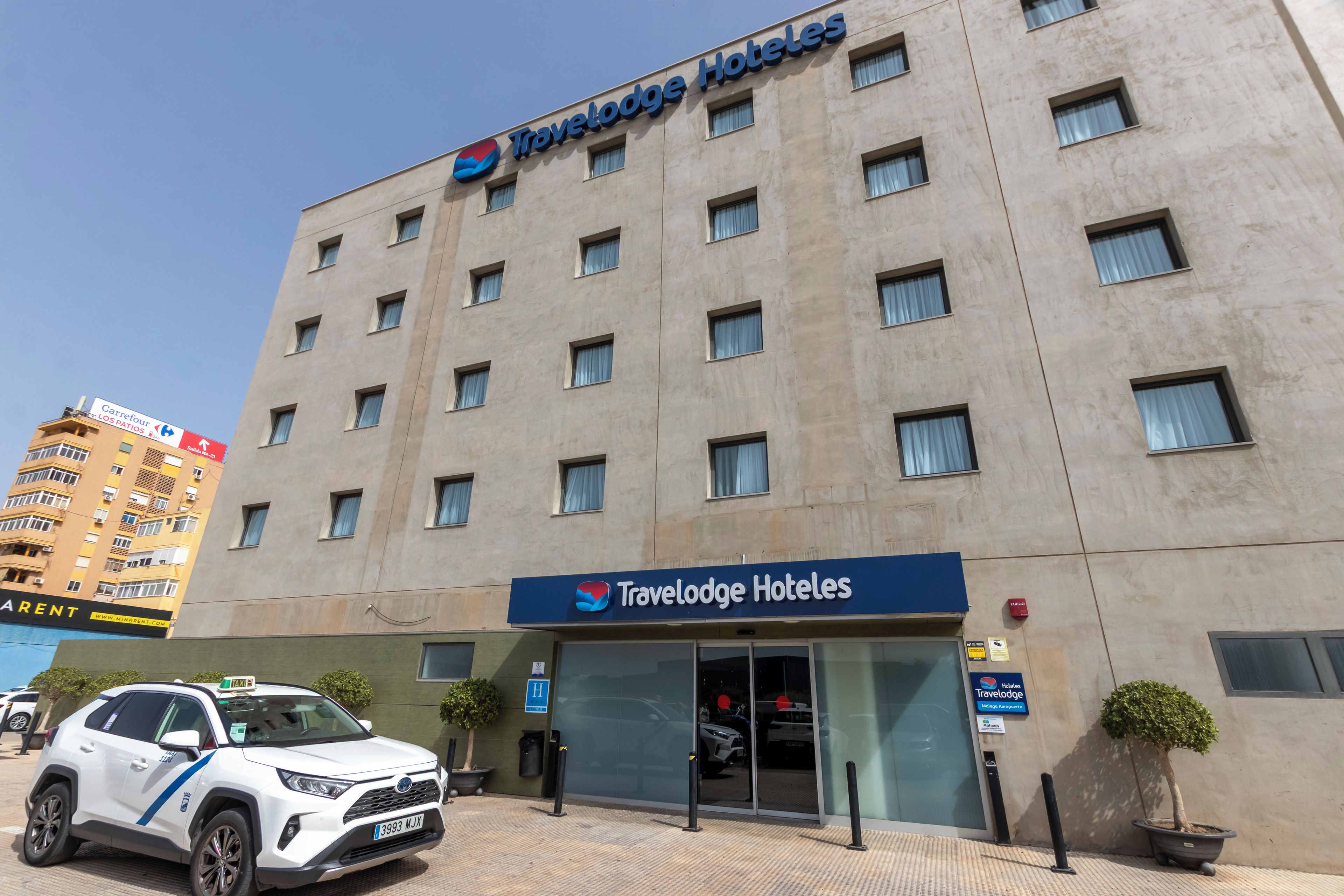 Un hotel Travelodge con fachada moderna, múltiples ventanas y una entrada visible.