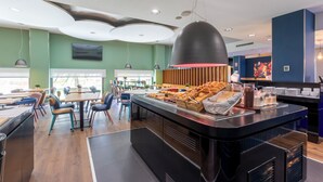 A modern restaurant with a buffet counter, wooden paneling, and a variety of food items. - Travelodge Malaga Aeropuerto (Málaga)