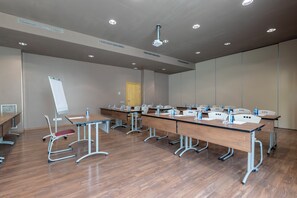 Ein Konferenzraum mit langen Tischen, Stühlen und einer Whiteboard-Tafel.
