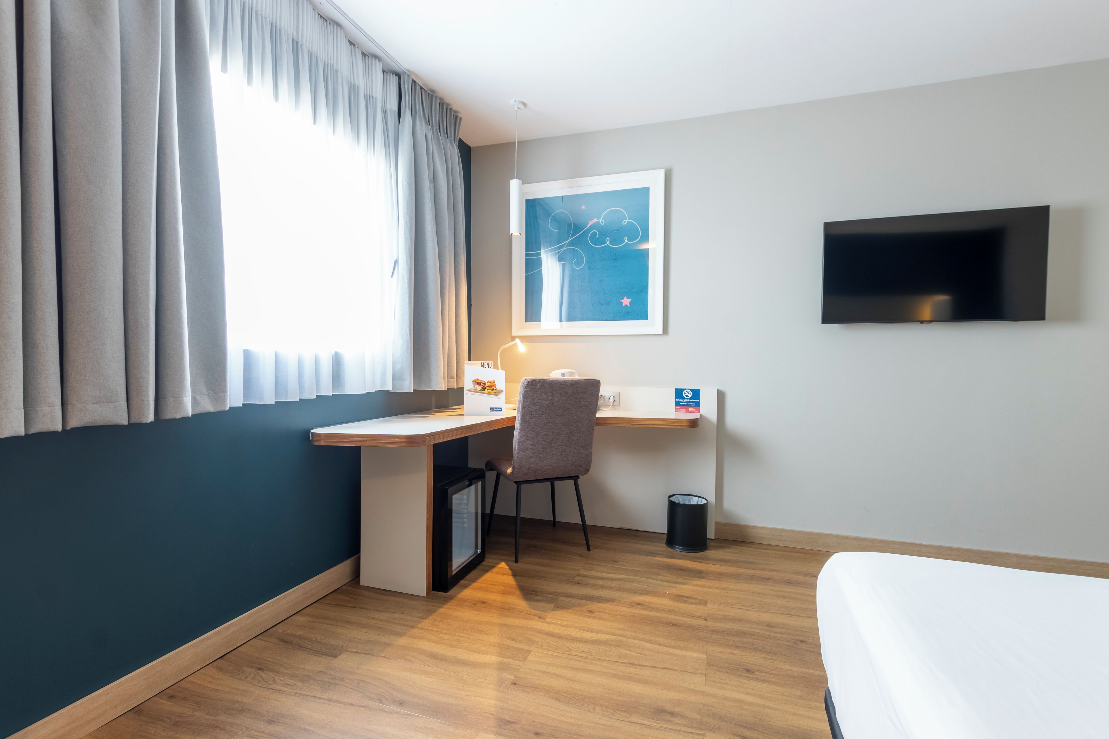 Et hotelværelse med et skrivebord, stol og en seng.