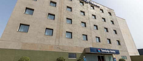 Un bâtiment d’hôtel Travelodge avec une façade plate, de nombreuses fenêtres et une enseigne au-dessus de l’entrée.