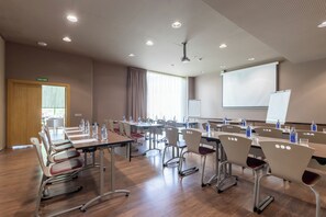 Ein Konferenzraum mit Tischen, Stühlen und einer Projektionsleinwand.