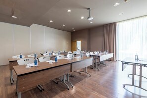 Ein Konferenzraum mit langen Tischen, Stühlen und einem Projektor.