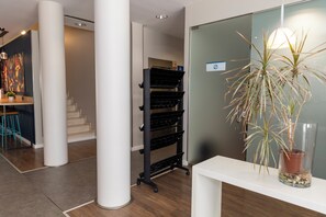A modern interior with a white reception desk, a black storage rack, and a potted plant. - Travelodge Malaga Aeropuerto (Málaga)