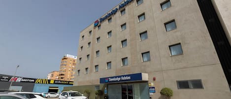 A Travelodge Hotel with a modern facade, multiple windows, and a parking area with cars.