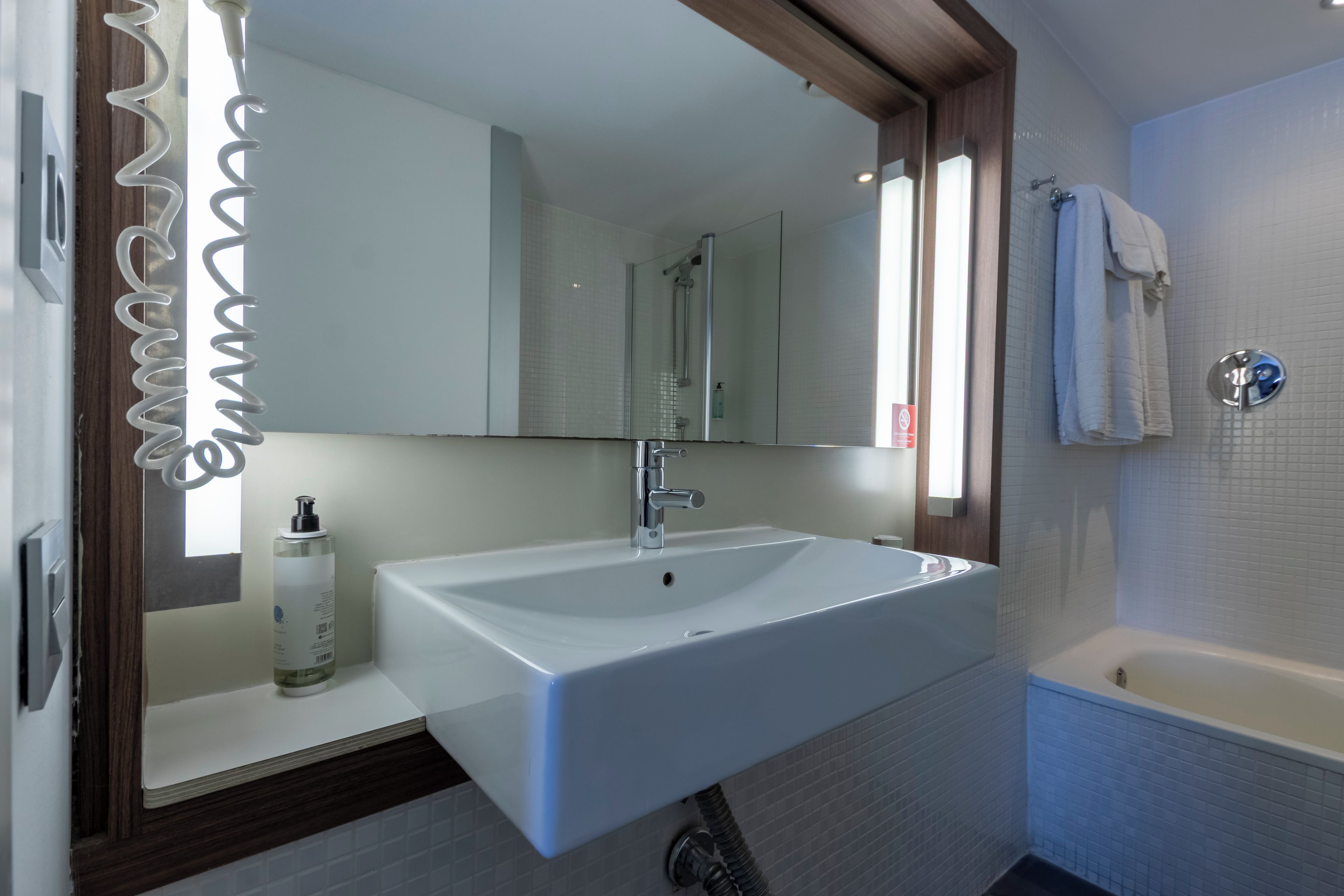 A bathroom with a white sink, a mirror, a shower, and a bathtub.