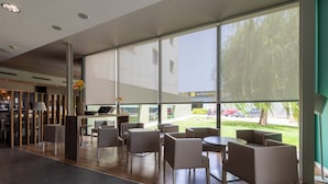 Un espace de détente intérieur moderne, doté de grandes fenêtres, d’un comptoir d’accueil et offrant une vue sur l’extérieur.
