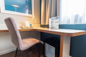 Un escritorio en esquina con una silla, un refrigerador pequeño, una cafetera, un dispensador de agua y un menú en la pared.