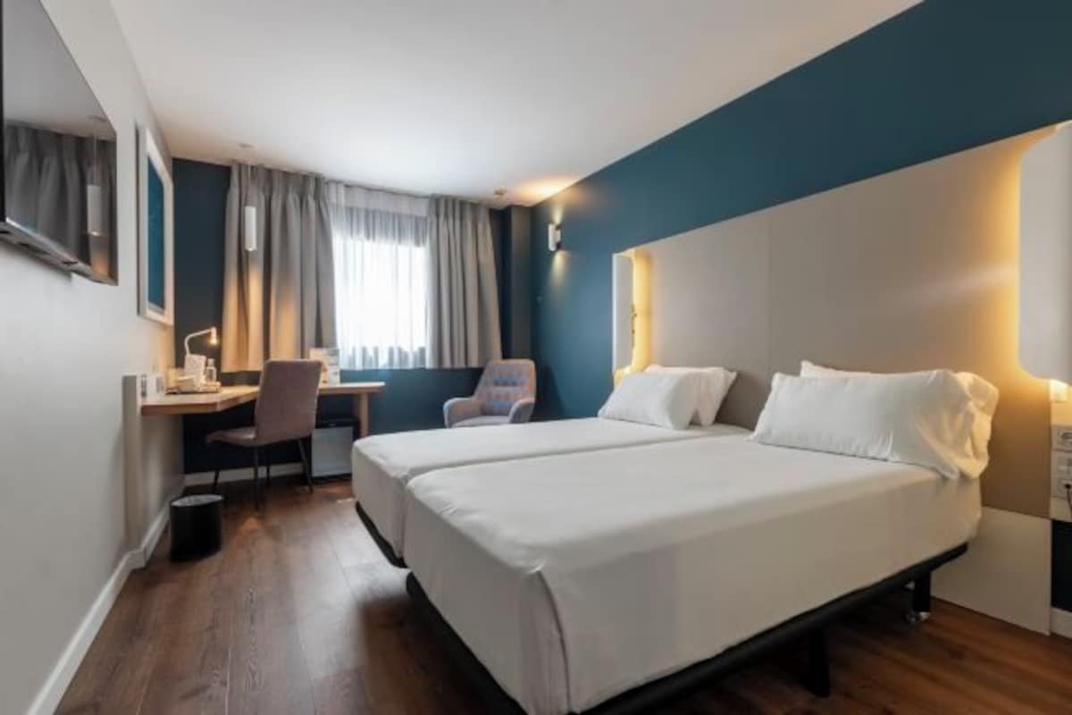 Una habitación de hotel con dos camas, un escritorio y una silla.