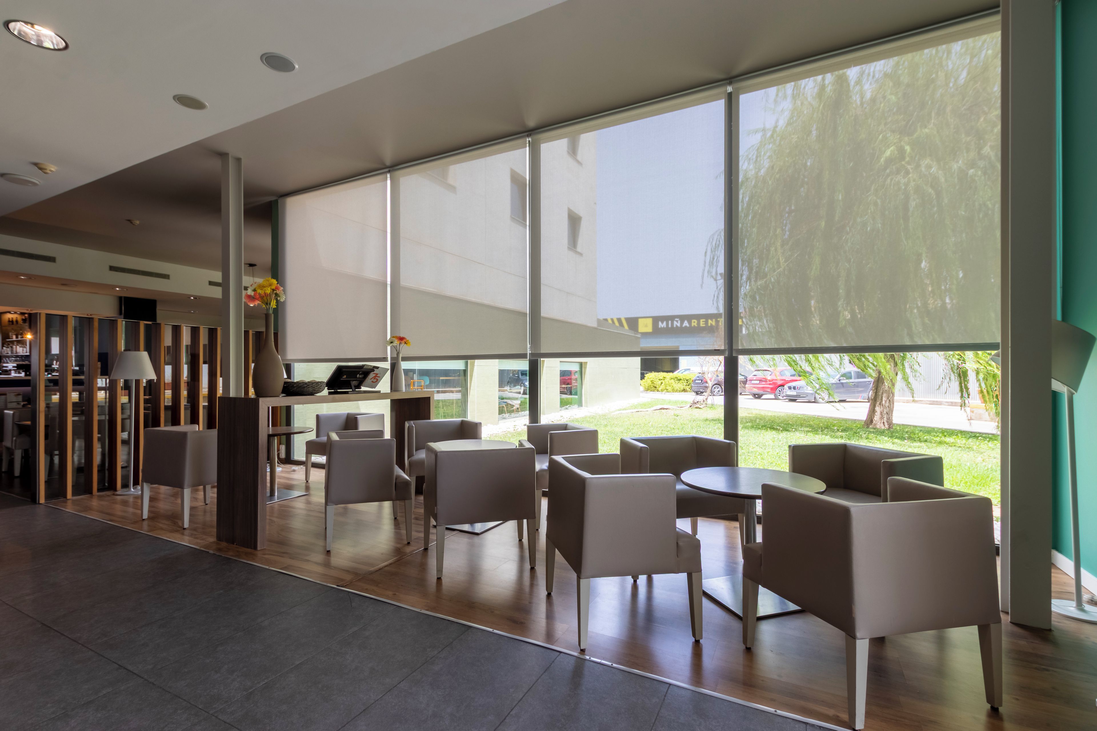 Un área de estar moderna en el interior, con amplias ventanas, un mostrador de recepción y vistas al exterior.