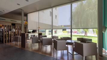 Un área de estar moderna en el interior, con amplias ventanas, un mostrador de recepción y vistas al exterior.