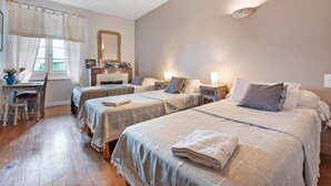 Quarto de hotel com duas camas, uma escrivaninha, uma cadeira e um espelho.