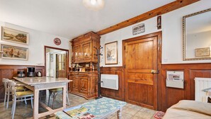 Uma cozinha aconchegante com armários de madeira, uma mesa de jantar com cadeiras e um pequeno banco com revistas.