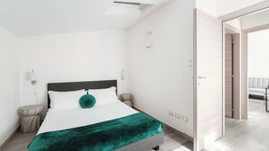 A modern bedroom with a bed, bedside tables, and a light switch on the wall. - Boheme Loft (Como)