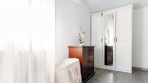 A room with a wooden cabinet, a white wardrobe, and a beige bag on the floor. - Boheme Loft (Como)