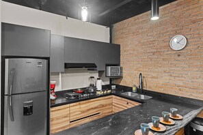 Eine moderne Küche mit Backsteinwand, Edelstahlgeräten und einer schwarzen Arbeitsplatte.