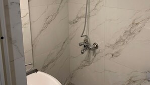 A bathroom with a shower, a sink, and marble walls.