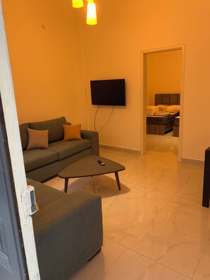 Una sala de estar con un sofá, una mesa de centro y un televisor de pantalla plana montado en la pared.