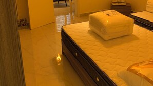 A hotel room with a large bed, a bedside table, a chair, and a window with bars.