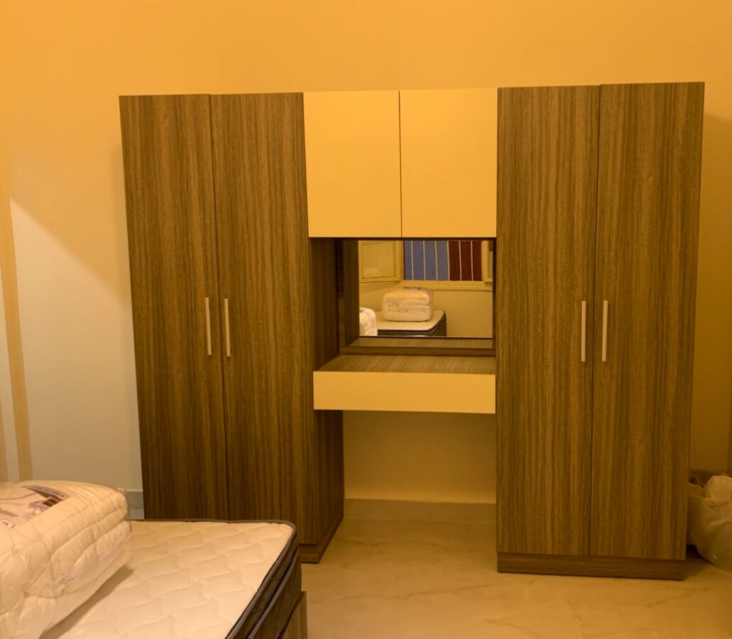 A bedroom with a bed, a bedside table, a wardrobe, and a mirror.