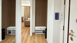 A hotel hallway with wooden flooring, a mirrored wall, and a door with a number sign. - House Gordiani Comfort Stay (Roma)
