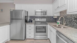 A kitchen with white cabinetry, stainless steel appliances, a microwave, a toaster, and a sink.