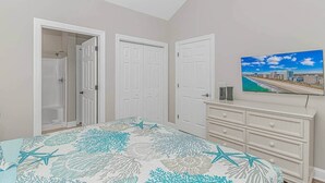 Un dormitorio con cama, televisor, cómoda y armario con ducha.