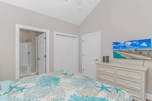 Une chambre à coucher comprenant un lit, une télévision, une commode et un placard avec une douche.