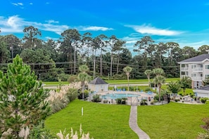 A residential area with a swimming pool, a small building, and a large house in the background.