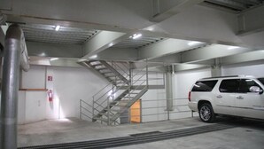 A parking garage with a white SUV parked near a stairwell. - Rolovi Xalapa Hotel (Xalapa)