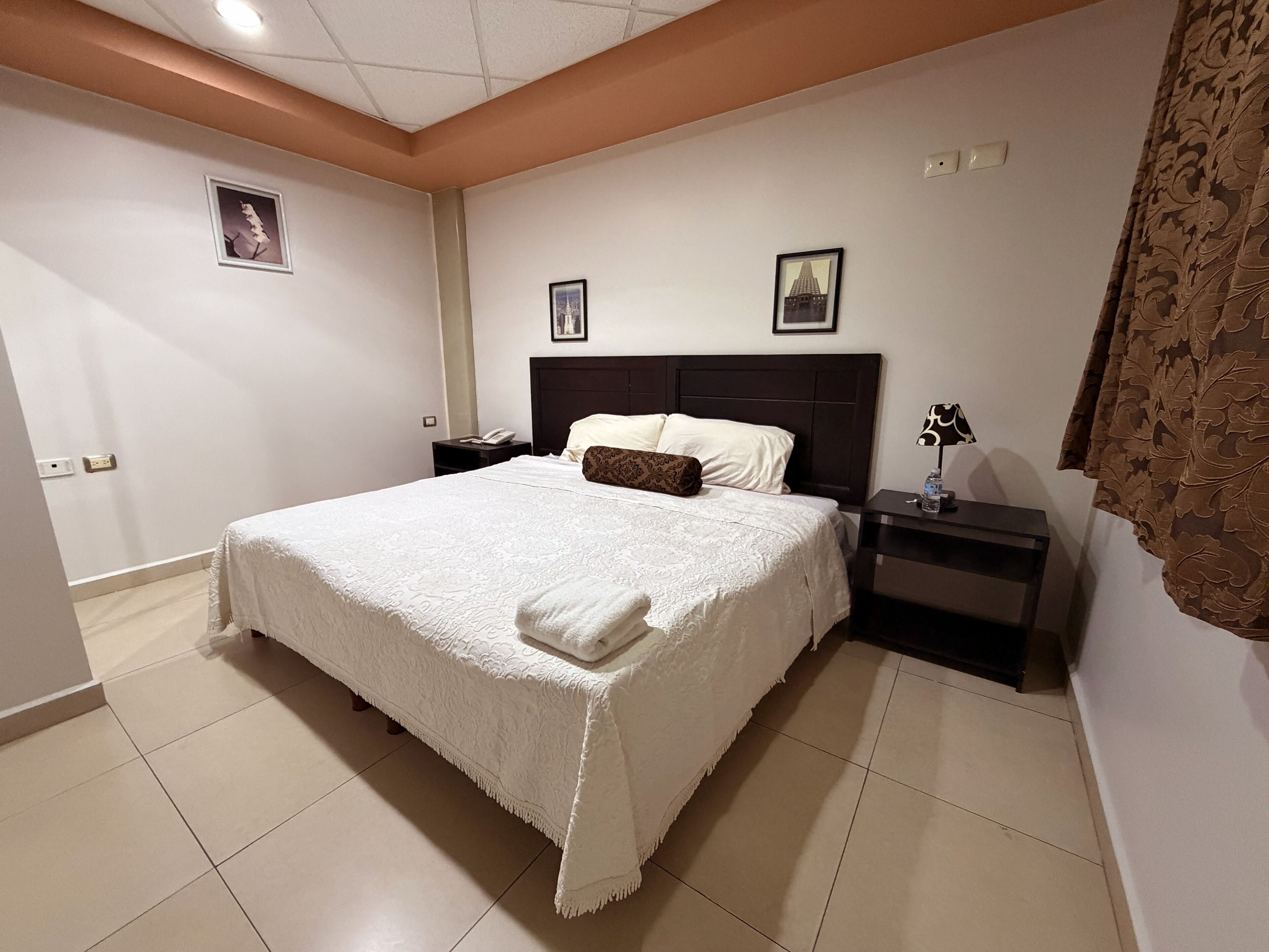 A neatly arranged bedroom with a large bed, two bedside tables, and a nightstand.