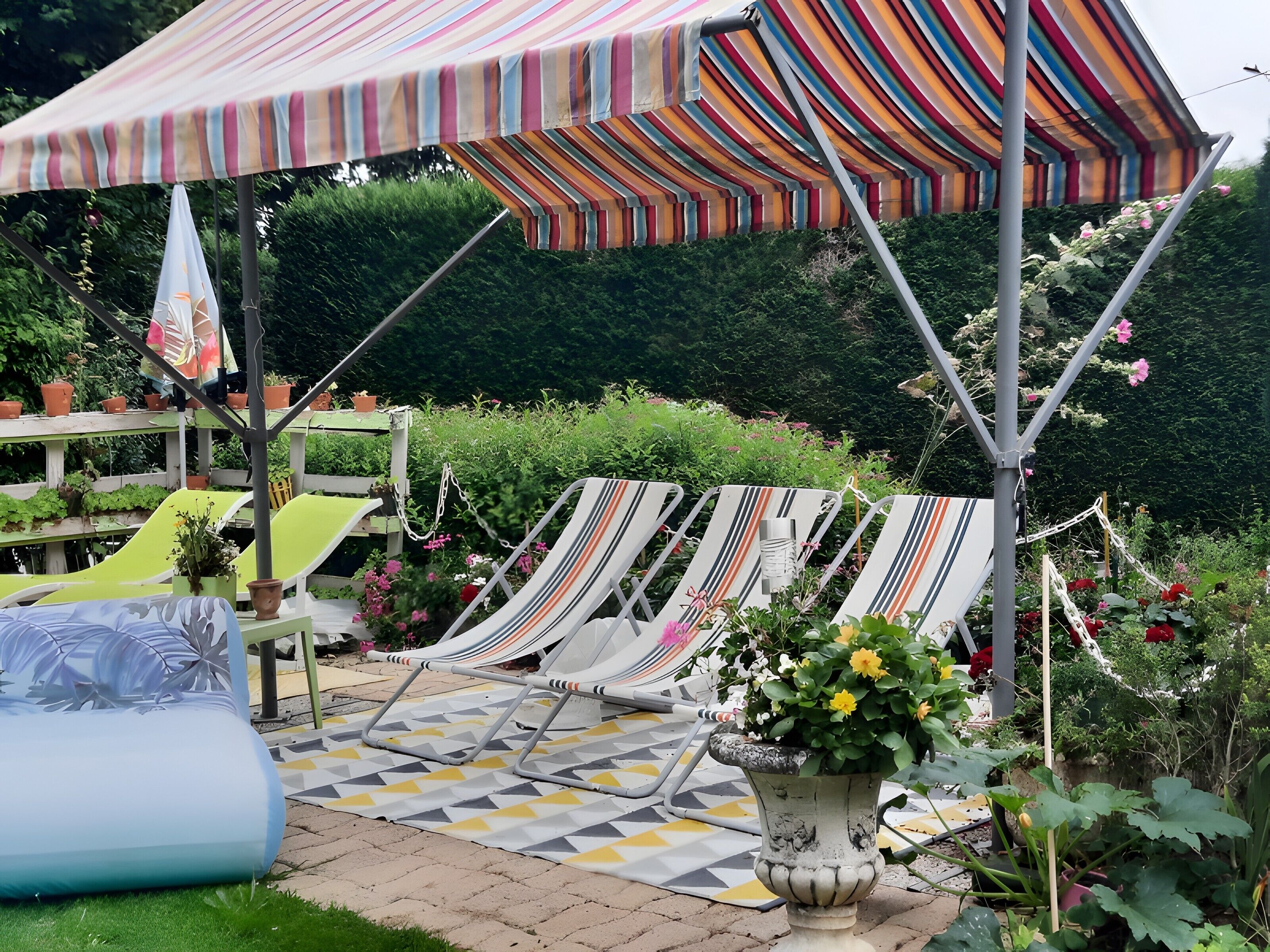Une terrasse agrémentée de parasols à rayures, de chaises longues et de plantes en pot.
