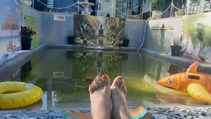 Zona de piscina con un mural, juguetes inflables y una estatua de Buda.